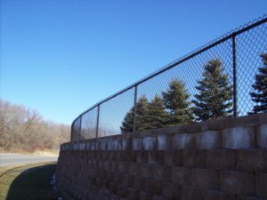 a black chainlink fence on a tall brick wall