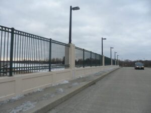 black decorative fence built in between brick columns on a bridge