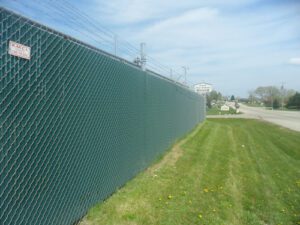 chainlink security fence with barbed wire and green slats