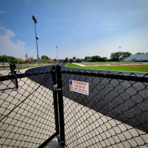 a black chainlink fence around a football field with the patriot fence logo
