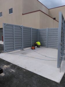 a patriot fence worker cleaning up around a newly built gray privacy fence