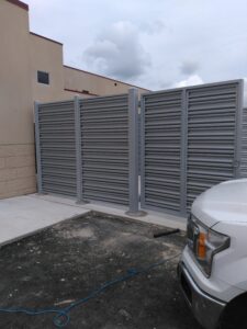 the side of a gray privacy fence with the front gate open