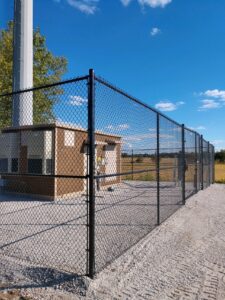 a tall black chainlink fence with a gate in the middle