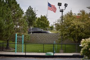 a black chainlink fence around a park with an American flag in the background