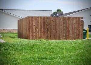 a wooden privacy fence built around a trash receptacle