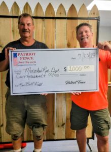 a large check for 1000 being held by a patriot fence employee and recipient