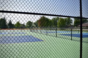 closeup of a black chainlink fence outside of a tennis court